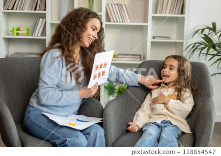 Long-haired cute girl working with a speech therapist and looking attentive 118854547