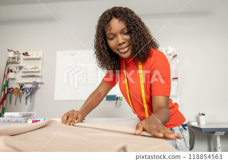 Dressmaker in orange tshirt tailoring fabric for a new dress 118854563