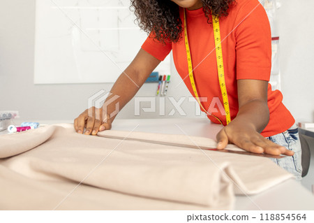 Dressmaker in orange tshirt tailoring fabric for a new dress 118854564