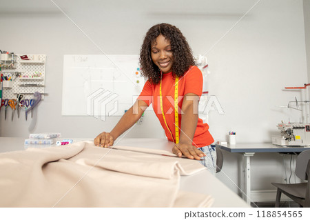 Dressmaker in orange tshirt tailoring fabric for a new dress 118854565