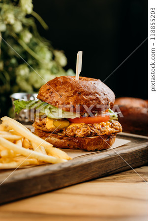 Juicy pulled pork burger with cheese, lettuce, and pickles served with crispy French fries on board 118855203