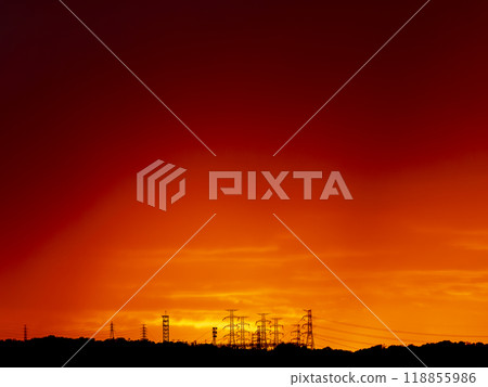A red sunrise and power transmission towers lined up in the mountains 118855986