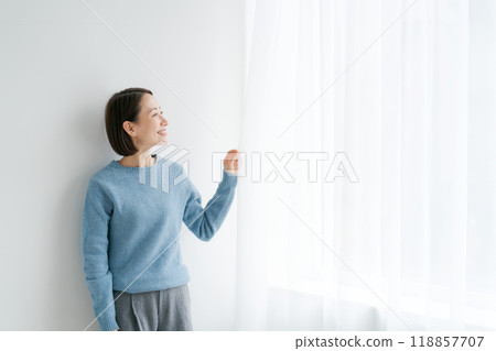 Woman opening the curtains and looking outside 118857707