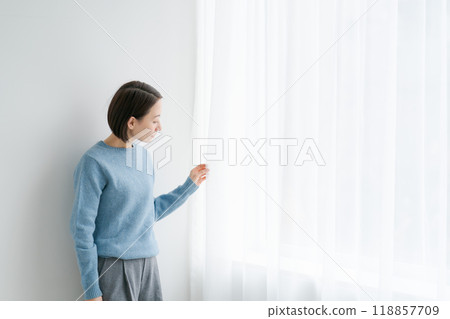 Woman opening the curtains and looking outside 118857709