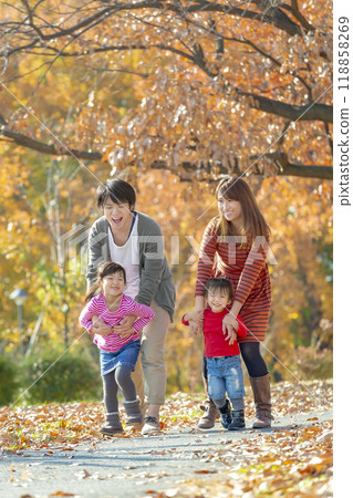 A family of four playing in the autumn leaves park 118858269