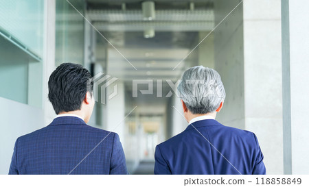 Back view of two business people walking down a building's corridor 118858849