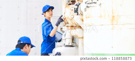 A group of engineers inspecting factory piping using a tablet 118858873