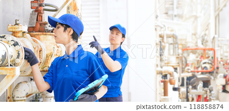 A group of engineers inspecting factory machines and piping using a tablet 118858874