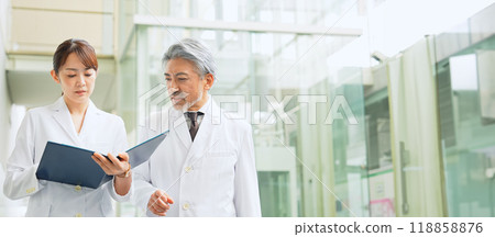 身穿白大褂的醫生和研究人員在設施內走動時交談 身穿白大褂的醫生和研究人員在設施內走動時交談 118858876