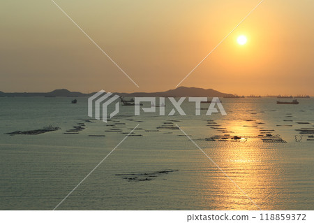 Sea is filled with cargo ships and fishing boats at dusk. 118859372