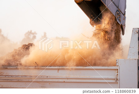 Backhoe loading soil into heavy duty dump truck at construction site. Crawler excavator transporting dirt with powerful bucket. Heavy construction machinery. Industrial earthmoving equipment in action 118860839