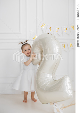 Little girl celebrating second birthday with big balloon indoors 118861400