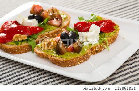 Toasts with guacamole, fresh vegetables, feta cheese 118861831