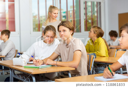 Schoolgirl peeks in a boys notebook during classes in school class Schoolgirl peeks in a boys notebook during classes in school class 118861833