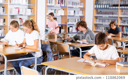 Teenage boys and girls in library Teenage boys and girls in library 118862069