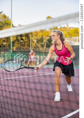 Sporty teenage girl tennis player playing tennis at court. View through tennis net 118862097