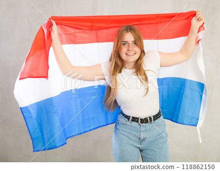 smiling girl in arms raised above head holds canvas of national flag of Netherlands 118862150