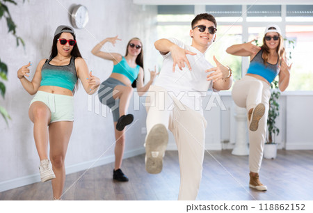 Guy and group of young girls in dark glasses and ball cap dance modern Jazz-modern in fitness club Guy and group of young girls in dark glasses and ball cap dance modern Jazz-modern in fitness club 118862152