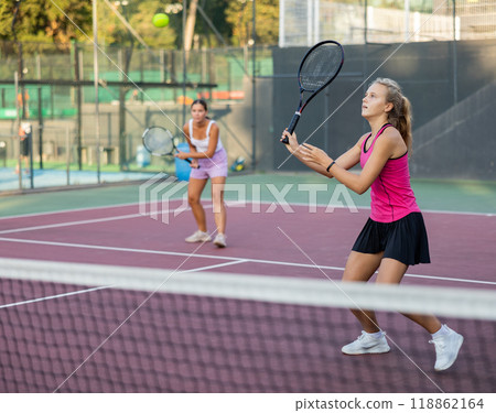 Girl playing tennis ball friendly match on outdoors court Girl playing tennis ball friendly match on outdoors court 118862164