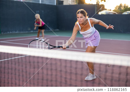 Sporty woman plays tennis on court. View through tennis net Sporty woman plays tennis on court. View through tennis net 118862165