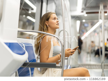 Young woman sitting in subway car with phone 118862189
