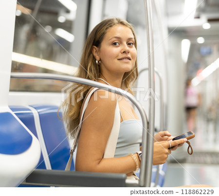 Young woman is sitting in subway car with phone, getting to work, school. 118862229