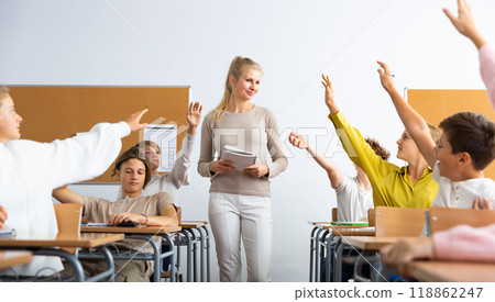 Pupils raising hands during lesson in school Pupils raising hands during lesson in school 118862247