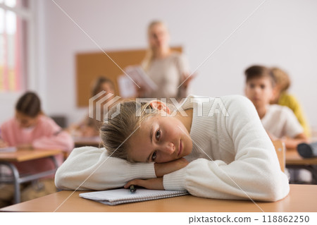 Teenager girl lying on table during lesson Teenager girl lying on table during lesson 118862250
