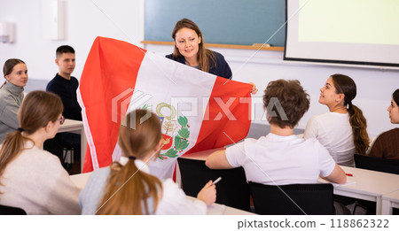 Teenage students in class and listening carefully to female teacher holding Peru flag in hands Teenage students in class and listening carefully to female teacher holding Peru flag in hands 118862322