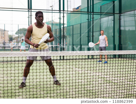 African american man and his partner playing paddle tennis on padel court 118862399