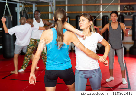 Men and women exercising self-protection moves in gym Men and women exercising self-protection moves in gym 118862415
