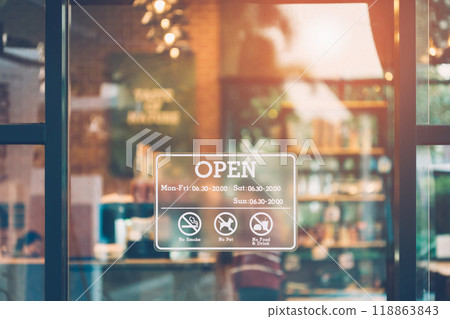 Stickers showing opening and closing times. Close up an open sign on the front window of a coffee shop or cafe and a blurred, bokeh image inside the shop. 118863843