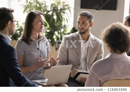 Engaged Caucasian businesswoman with laptop sharing ideas with colleagues Engaged Caucasian businesswoman with laptop sharing ideas with colleagues 118863896