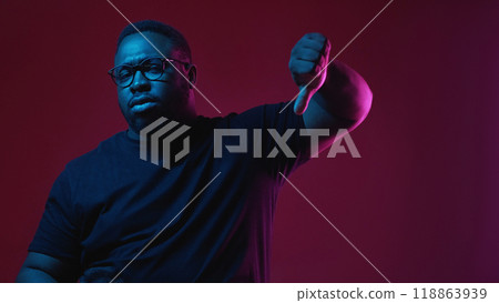 Dislike gesture. Negative opinion. Disappointed unhappy skeptic man with disapproval facial expression thumb down sign isolated on burgundy background. 118863939