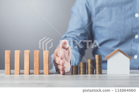 Businessman uses his hand to stop wooden blocks from falling, symbolizing the protection of assets and strategic decision-making in managing resources effectively, domino effect and risk management 118864060