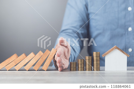 Businessman uses his hand to stop wooden blocks from falling, symbolizing the protection of assets and strategic decision-making in managing resources effectively, domino effect and risk management Businessman uses his hand to stop wooden blocks from falling, symbolizing the protection of assets and strategic decision-making in managing resources effectively, domino effect and risk management 118864061