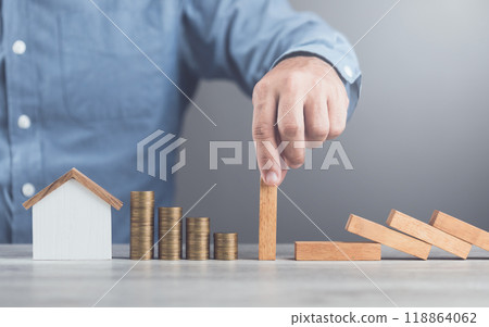 Businessman uses his hand to stop wooden blocks from falling, symbolizing the protection of assets and strategic decision-making in managing resources effectively, domino effect and risk management 118864062