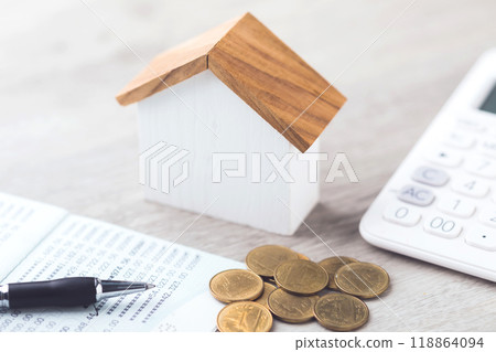 House model, coin pile, calculator, and savings account passbook are placed on the table, symbolizing the concept of house financing, savings, and financial planning for real estate investment 118864094