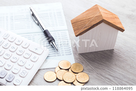 House model, coin pile, calculator, and savings account passbook are placed on the table, symbolizing the concept of house financing, savings, and financial planning for real estate investment 118864095