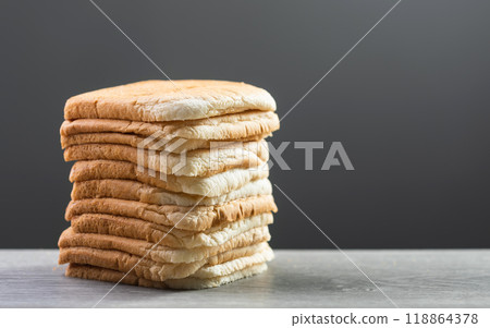 Slices of bread stacked on a gray wooden table against a dark gray background. The image symbolizes the connection between food, nutrition, and maintaining good health. 118864378