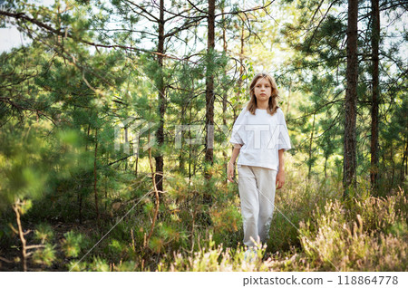 A child exploring a serene forest trail on a sunny day, surrounded by lush trees  118864778