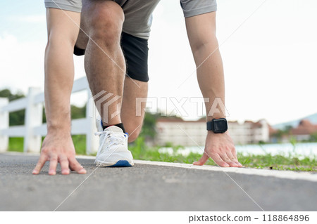 A cropped image of an active man in sportswear in a ready-to-run position, preparing to sprint. A cropped image of an active man in sportswear in a ready-to-run position, preparing to sprint. 118864896