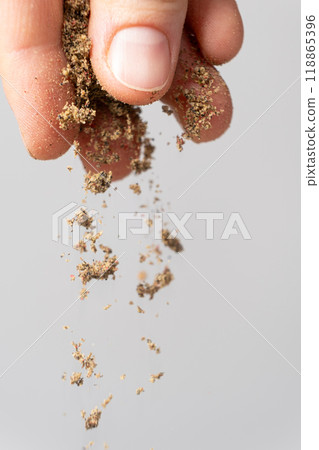 Hand pouring ground peppercorn mixture, black, white, red and green pepper 118865396