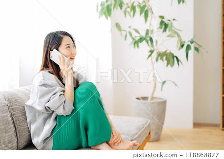 一個女人坐在沙發上打個電話 118868827