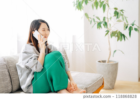 一個女人坐在沙發上打個電話 118868828