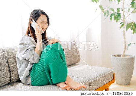一個女人坐在沙發上打個電話 118868829