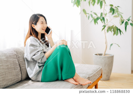 一個女人坐在沙發上打個電話 118868830