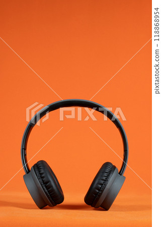 Black headphones positioned against a bright orange background 118868954
