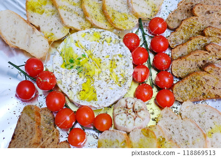 Preparation of a delicious starter of ham, cheese, red grapes, purple grapes, cherry tomato, jelly, fresh olives. Delicious board of hams and cheeses with fruit to share at a table gourmet party 118869513