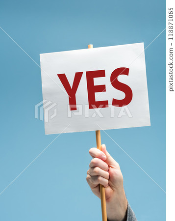 Male hand holding sign with the word YES against a blue background Male hand holding sign with the word YES against a blue background 118871065
